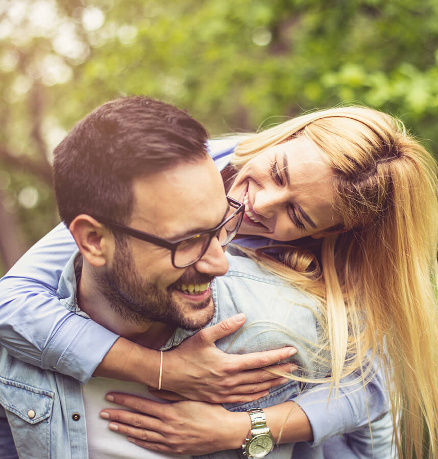 Adult woman getting hugging her husband from behind.